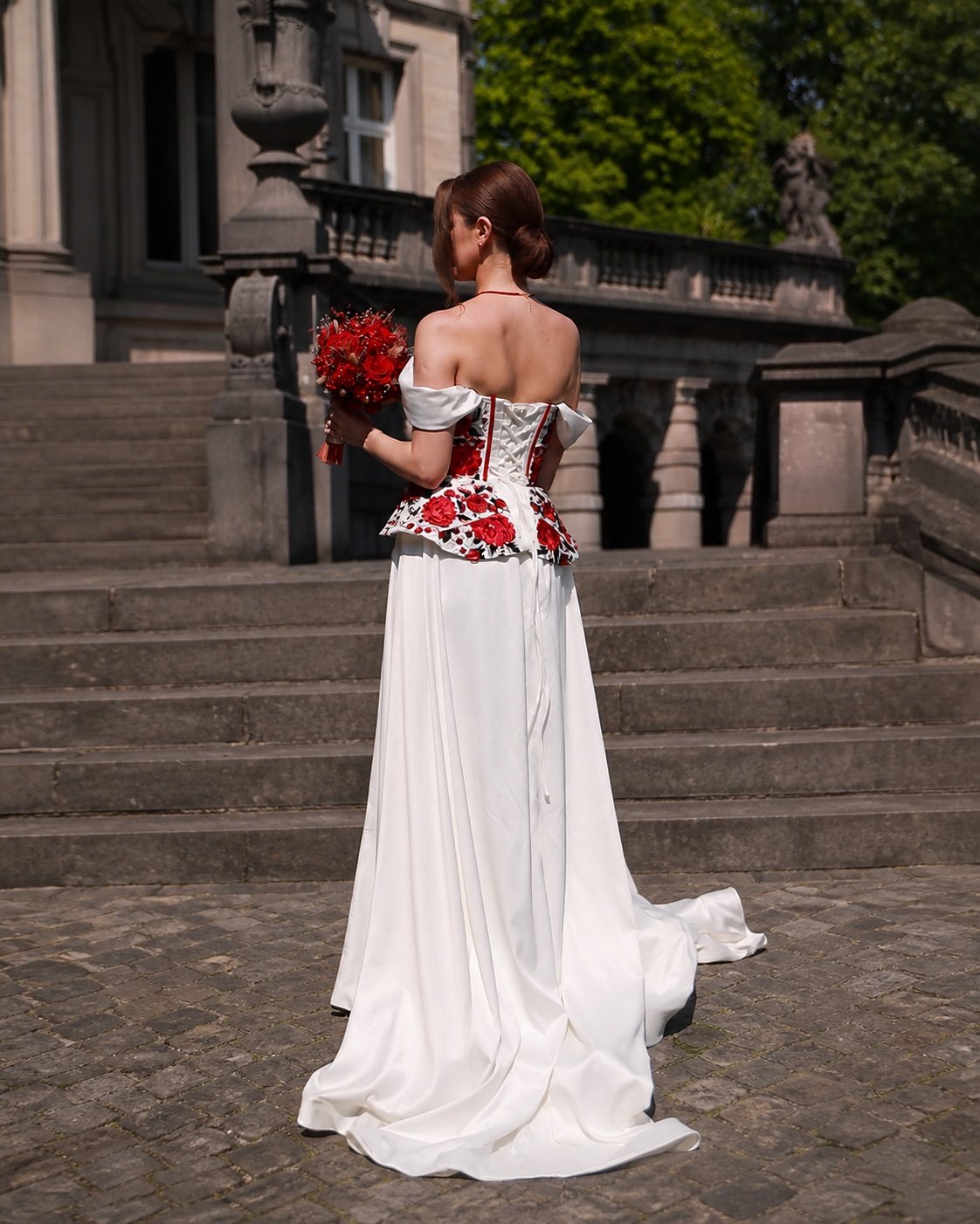 Mariée tenant un bouquet rouge créé par Harmonie